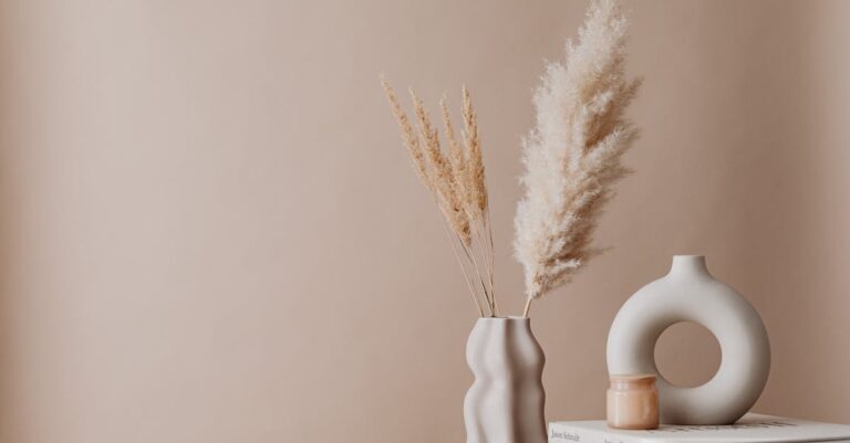 A minimalist aesthetic featuring vases with pampas grass and books on a beige backdrop.